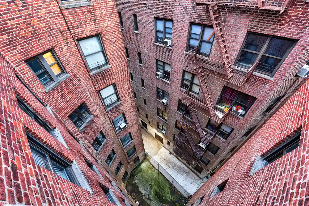 Courtyard of a brick apartment building with fire escapes
