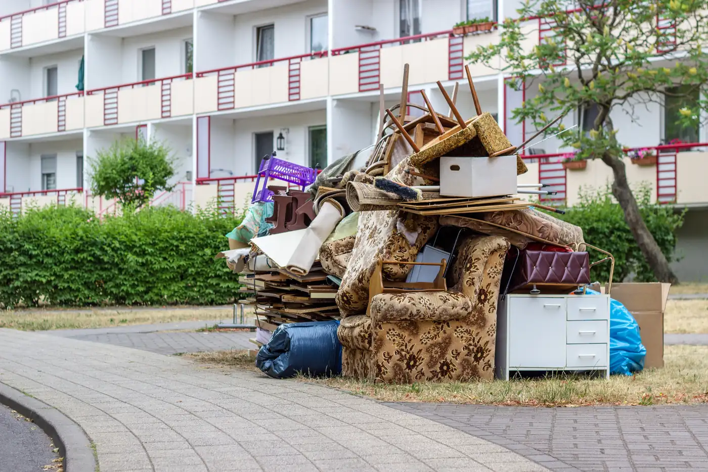Pile of dumped furniture and household items outside an apartment building