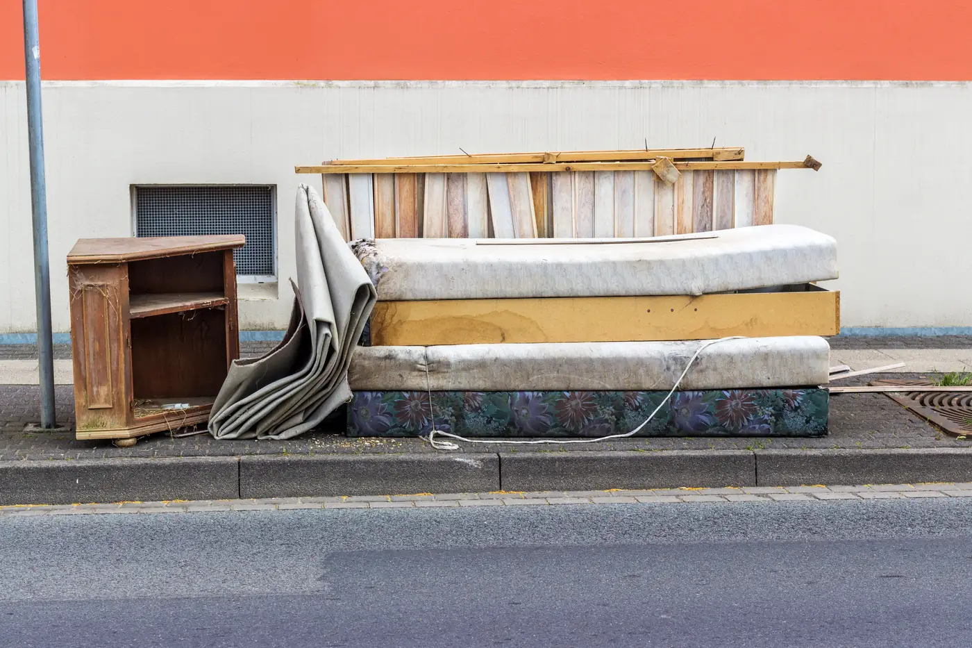 Mattresses, furniture, and carpet dumped along a sidewalk