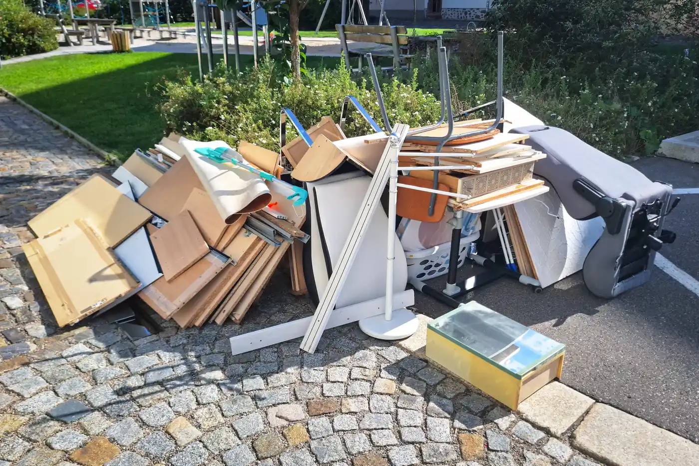 Illegally dumped furniture and household junk piled near a community playground